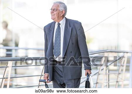 Smiling senior businessman leaving hotel View Large Photo Image Stock Photo - Smiling senior businessman leaving hotel. Fotosearch