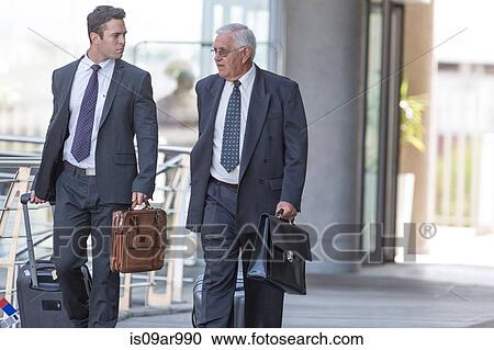 Two businessmen talking whilst leaving hotel View Large Photo Image Stock Image - Two businessmen talking whilst leaving hotel. Fotosearch