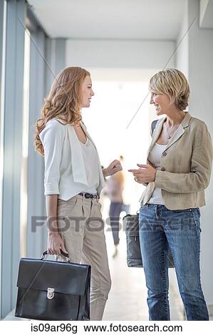 Stock Image - Two businesswomen talking in hotel corridor. Fotosearch