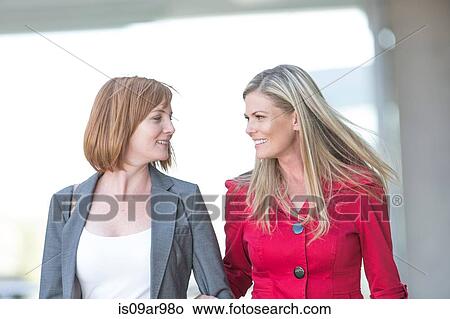 Two women friends walking and talking in city View Large Photo Image Picture - Two women friends walking and talking in city. Fotosearch