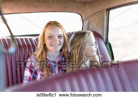 Two young girls sitting in back seat of car, smiling View Large Photo Image Stock Image - Two young girls sitting in back seat of car, smiling. Fotosearch