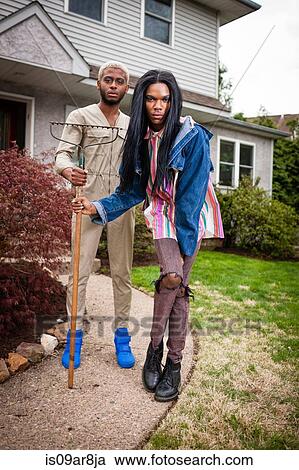 Stock Image - Two young men posing in front yard with rake. Fotosearch