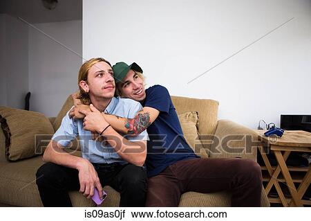 Two young men sitting on sofa, hugging View Large Photo Image Stock Image - Two young men sitting on sofa, hugging. Fotosearch