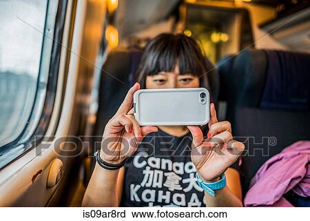 Woman on train using smartphone to take photograph View Large Photo Image Stock Image - Woman on train using smartphone to take photograph. Fotosearch