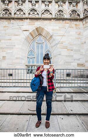 Stock Photograph - Woman taking selfie in front of Duomo Cathedral, Milan, Italy. Fotosearch