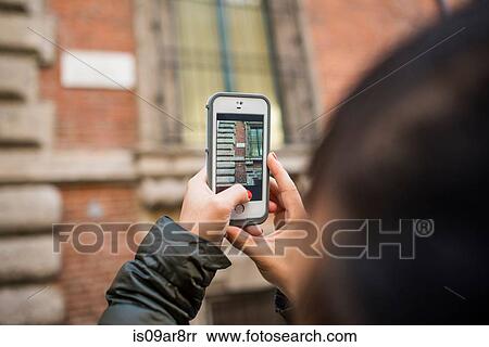 Woman using smartphone to take photograph of street sign View Large Photo Image Stock Photography - Woman using smartphone to take photograph of street sign. Fotosearch