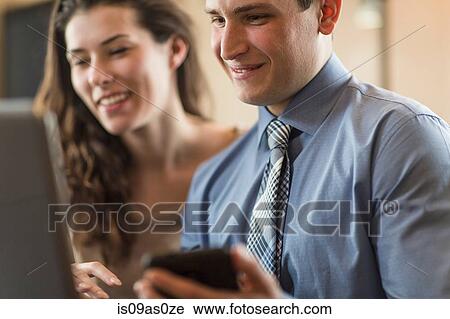 Stock Image - Young couple browsing laptop and smartphone at home. Fotosearch