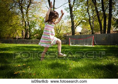 Stock Image - Young girl running in garden, low angle view. Fotosearch