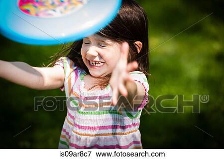 Stock Photo - Young girl throwing frisbee in garden. Fotosearch