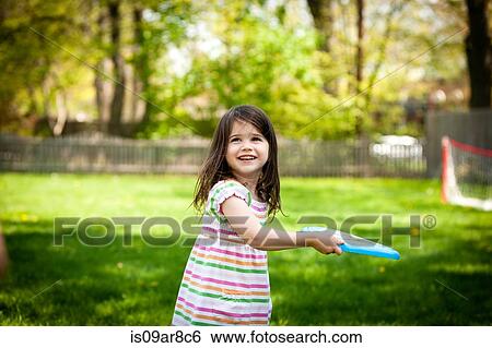 Stock Photograph - Young girl throwing frisbee in garden. Fotosearch