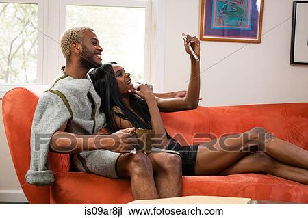 Young male couple lying on sofa, looking at smartphone View Large Photo Image Stock Image - Young male couple lying on sofa, looking at smartphone. Fotosearch