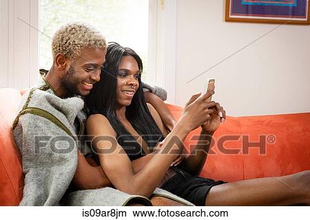 Young male couple on sofa, looking at smartphone View Large Photo Image Picture - Young male couple on sofa, looking at smartphone. Fotosearch