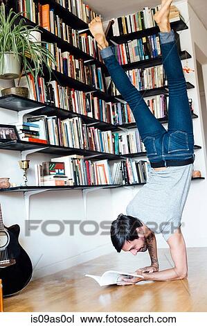 Young man reading book whilst doing forearm stand View Large Photo Image Stock Image - Young man reading book whilst doing forearm stand. Fotosearch
