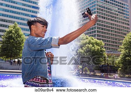 Young man taking a self portrait next to water fountain, Philadelphia, Pennsylvania, USA View Large Photo Image Picture - Young man taking a self portrait next to water fountain, Philadelphia, Pennsylvania, USA. Fotosearch