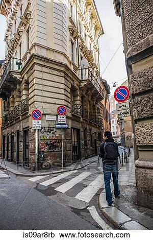 Stock Image - Young man walking through graffiti covered street, Milan, Italy. Fotosearch