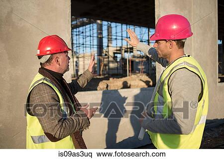 Stock Photography - Architect and builder discussing window frame on construction site. Fotosearch