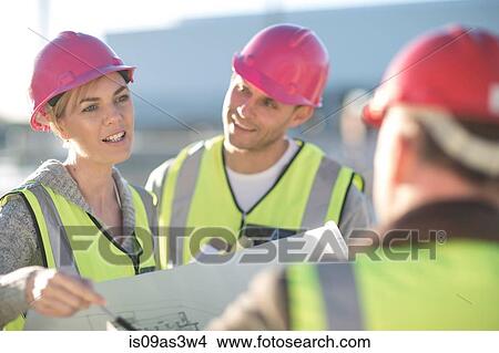 Picture - Architect and surveyors discussing blueprint on construction site. Fotosearch
