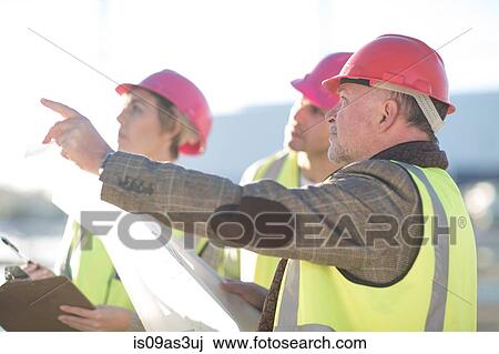 Stock Image - Architect and surveyors meeting on construction site. Fotosearch