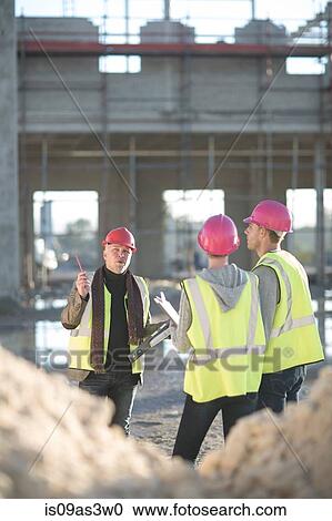 Stock Image - Architect explaining to builders on construction site. Fotosearch