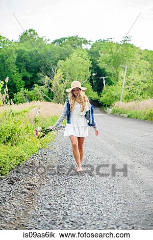 Bare footed young woman walking on rural gravel road carrying bunch of flowers View Large Photo Image Stock Image - Bare footed young woman walking on rural gravel road carrying bunch of flowers. Fotosearch