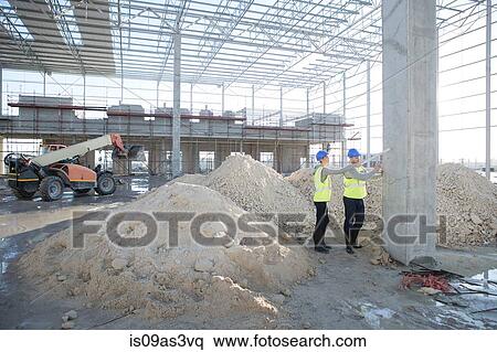 Stock Photography - Builder and architect marking pillar with spray can on construction site. Fotosearch