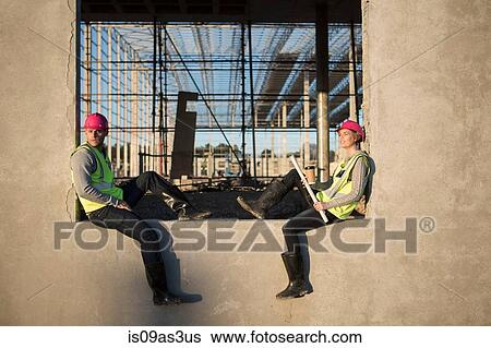 Stock Photograph - Builder and architect sitting on window frame at construction site. Fotosearch