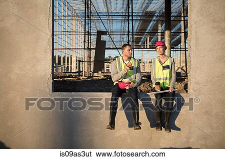 Stock Photograph - Builder and architect taking a break on construction site. Fotosearch