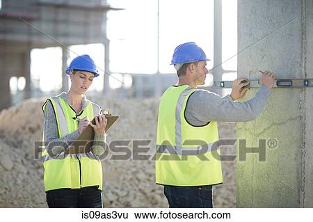 Stock Photograph - Builder using spirit level on construction site pillar. Fotosearch