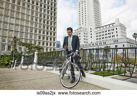 Business man on elevated walkway with bicycle looking at smartphone, Los Angeles City Hall, California, USA View Large Photo Image Stock Photo - Business man on elevated walkway with bicycle looking at smartphone, Los Angeles City Hall, California, USA. Fotosearch