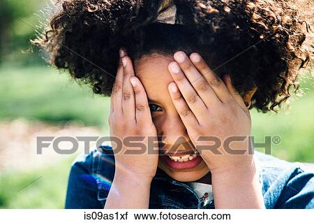 Stock Image - Close up portrait of girl covering face with hands. Fotosearch