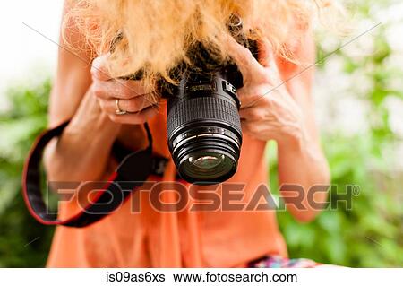 Stock Photograph - Cropped shot of woman with red hair photographing downward with digital SLR. Fotosearch
