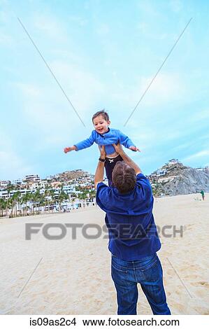 Father lifting son, on beach, rear view View Large Photo Image Picture - Father lifting son, on beach, rear view. Fotosearch