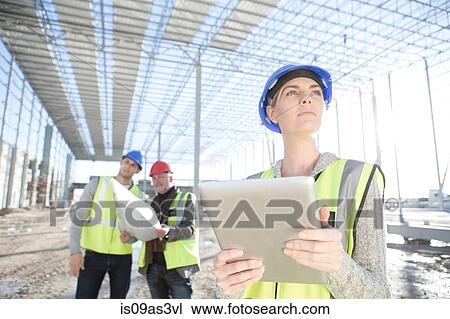 Female surveyor looking up from digital tablet on construction site View Large Photo Image Stock Image - Female surveyor looking up from digital tablet on construction site. Fotosearch