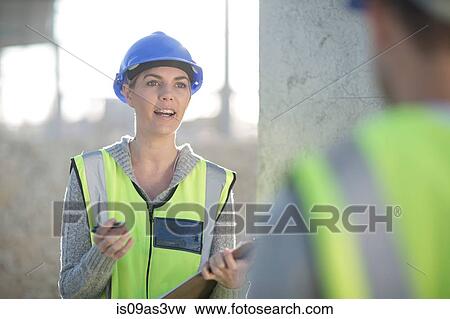 Female surveyor with clipboard talking to builder on construction site View Large Photo Image Stock Photo - Female surveyor with clipboard talking to builder on construction site. Fotosearch