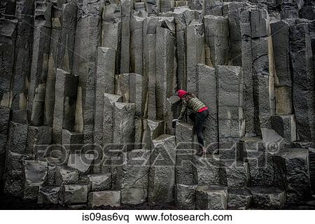Stock Photography - Female tourist climbing up rock formation, Reynisfjara, Iceland. Fotosearch