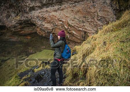 Female tourist photographing at Seljalandsfoss waterfall, Iceland View Large Photo Image Stock Photo - Female tourist photographing at Seljalandsfoss waterfall, Iceland. Fotosearch