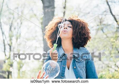 Front view of mid adult woman blowing bubbles, eyes closed, looking up View Large Photo Image Picture - Front view of mid adult woman blowing bubbles, eyes closed, looking up. Fotosearch