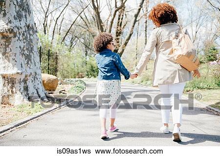 Full length rear view of mother and daughter walking holding hands View Large Photo Image Stock Photograph - Full length rear view of mother and daughter walking holding hands. Fotosearch