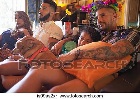 Stock Photography - Girl and family on living room sofa watching TV. Fotosearch