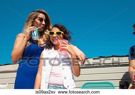 Stock Photo - Girl and her mother drinking juice on patio. Fotosearch