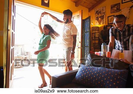 Stock Photo - Girl dancing and twirling with father in living room. Fotosearch