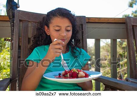 Girl eating fruit dessert on garden bench View Large Photo Image Stock Photo - Girl eating fruit dessert on garden bench. Fotosearch