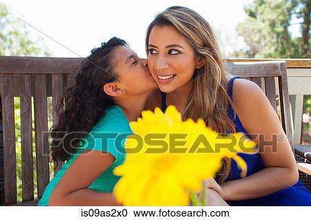 Girl kissing her mothers cheek on garden bench View Large Photo Image Stock Image - Girl kissing her mothers cheek on garden bench. Fotosearch
