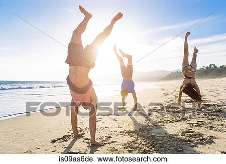 Group of friends doing handstands on beach View Large Photo Image Stock Image - Group of friends doing handstands on beach. Fotosearch