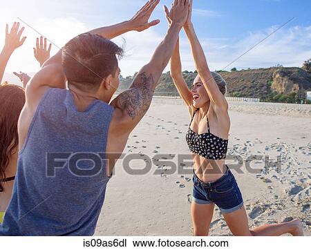 Stock Image - Group of friends fooling around on beach. Fotosearch