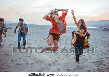Stock Photograph - Group of friends fooling around on beach. Fotosearch