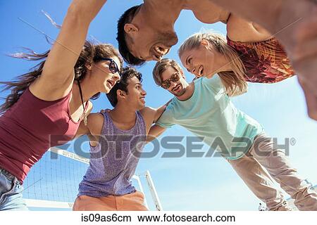 Group of friends in huddle on beach, low angle view View Large Photo Image Picture - Group of friends in huddle on beach, low angle view. Fotosearch