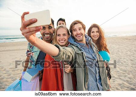 Picture - Group of friends on beach, taking self portrait with smartphone. Fotosearch
