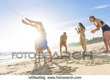 Group of friends on beach watching friend do handstand View Large Photo Image Stock Image - Group of friends on beach watching friend do handstand. Fotosearch