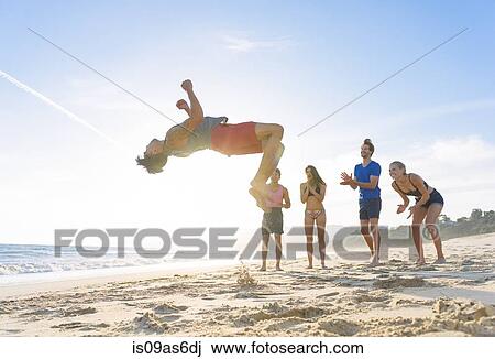 Group of friends on beach watching friend do somersault View Large Photo Image Stock Image - Group of friends on beach watching friend do somersault. Fotosearch